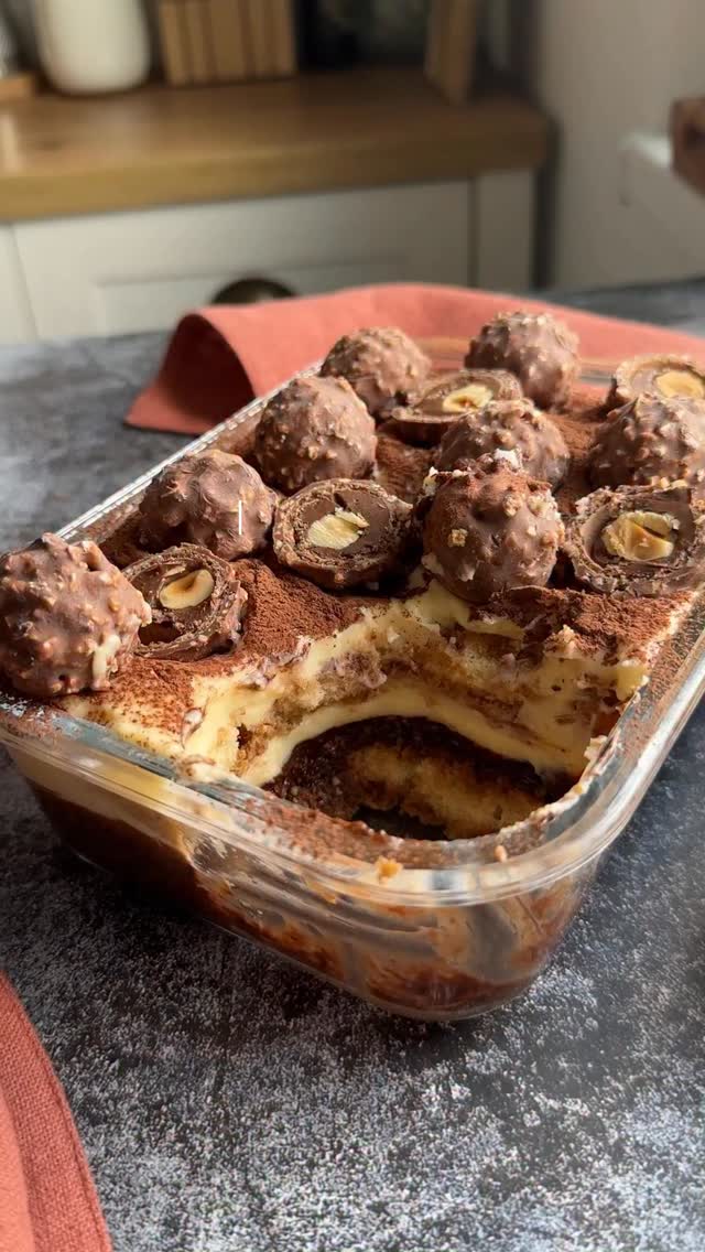 ⭐️Postez în fiecare zi câte o rețetă de tiramisu până la Crăciun! Tiramisu Rocher are cremă cu gust bogat de ciocolată plină cu alune crocante dar e super simplu de făcut!Ingrediente
✅Pentru crema de ciocolată :
150 ml frisca lichida
90 g ciocolata neagră (90%)
alune de pădure caramelizate și crocante (de la Lidl – raftul cu decorațiuni pentru prăjituri)✅Pentru crema tiramisu2 gălbenușuri de ou
250 g mascarpone
35 g zahăr pudră
½ linguriță extract de vanilie12-16 pișcoturi
200 ml cafea espresso neîndulcită6-7 bomboane Ferrero Rocher1. Am încălzit frișca lichidă și am adăugat ciocolata. Am amestecat până s-a topit iar crema a început să se îngroașe. La final am adăugat și alunele mărunțite și caramelizate.
2. Am înmuiat pișcoturile în cafea și am turnat crema deasupra. Am dat totul la frigider.
3. Între timp am mixat gălbenușurile de ou cu  zahăr pudră si vanilie, până am obținut o cremă deschisă la culoare. Apoi am adăugat și mascarpone. Am mixat din nou.
🔺Pentru cei care au o problemă cu gălbenușurile crude, acestea se pot bate pe baie de aburi. Sau se pot elimina cu totul din rețetă.
Am  întins jumătate din crema de mascarpone peste cea ciocolata  care între timp s-a răcit.
4. Am pus un nou strat de pișcoturi înmuiate în cafea, apoi din nou un strat de cremă de mascarpone.
5. Am pudrat cu cacao și am ornat cu Fererro Rocher.
Reteta e scrisă în descrierea clipului! Pofta buna!#tiramisu #retetesimple #retetesimple #100tiramisu #bucatarmaniac