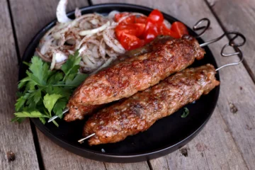 mici kebap la gratar pe frigarui serviti cu salata de ceapa si rosii